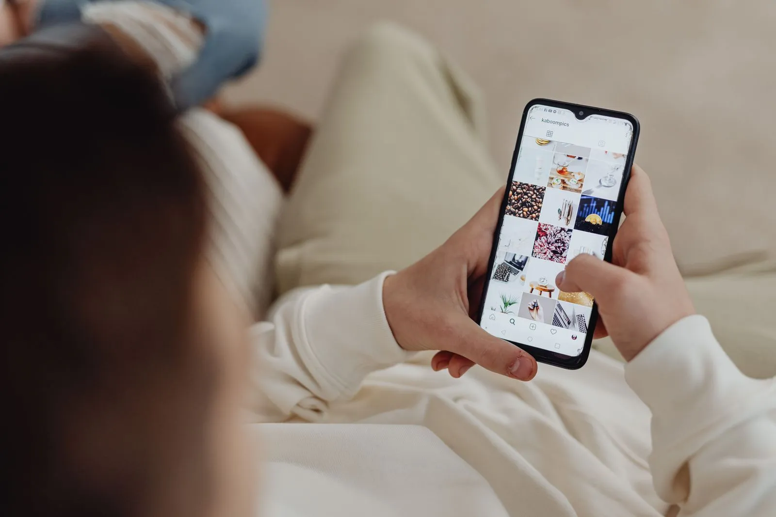 Hand holding a smartphone that shows an Instagram feed full of photos