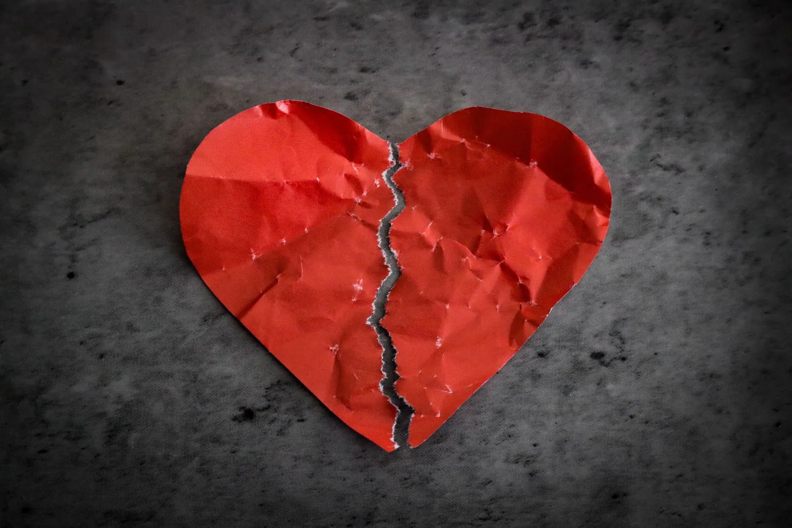 A torn red paper heart on a dark gray background