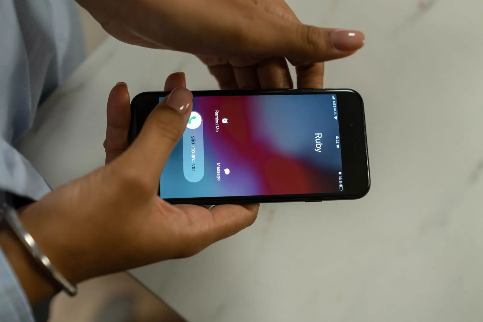 Hands holding a smartphone that shows an incoming call with a contact name on the screen