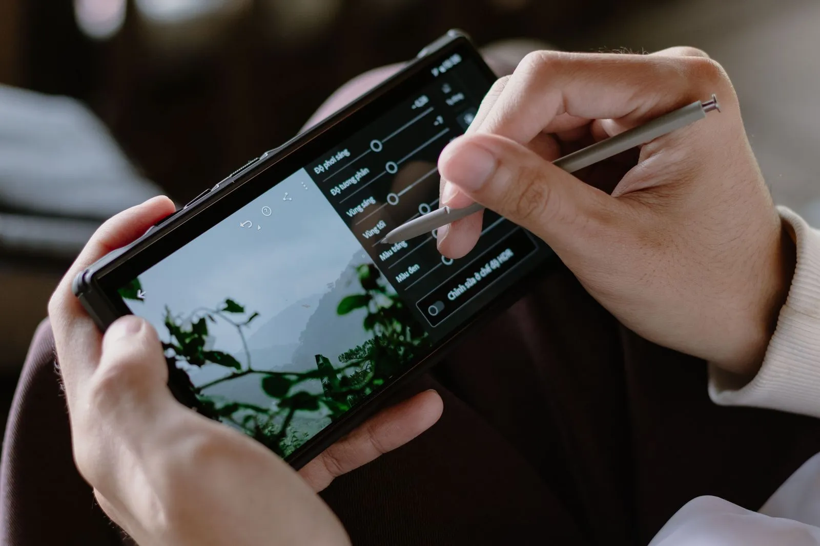 Hands adjusting exposure and contrast sliders in a smartphone photo editor