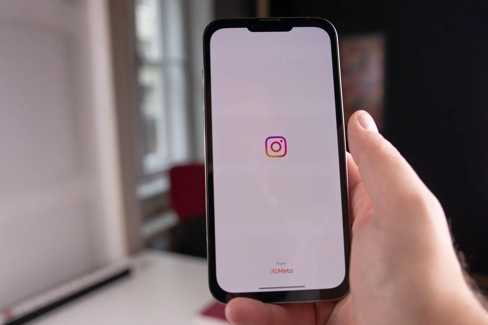 A hand holding a smartphone that shows the Instagram app's start screen