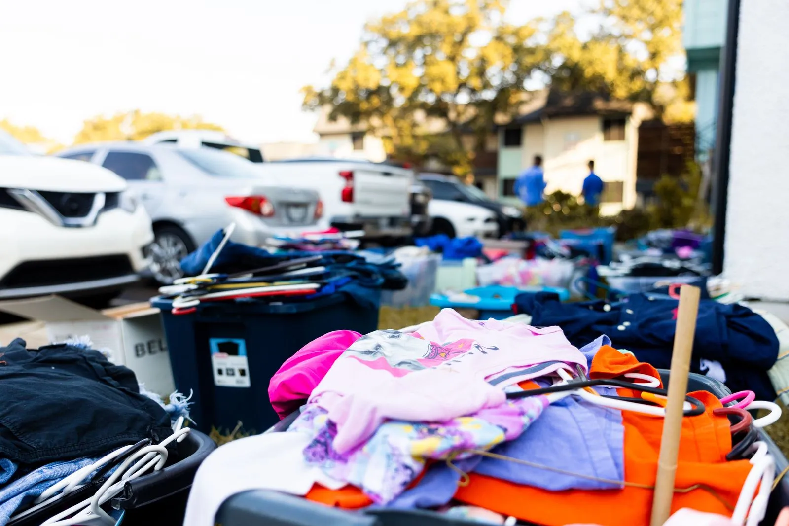 Clothes, bins and hangers laid out on a lawn at a suburban garage sale