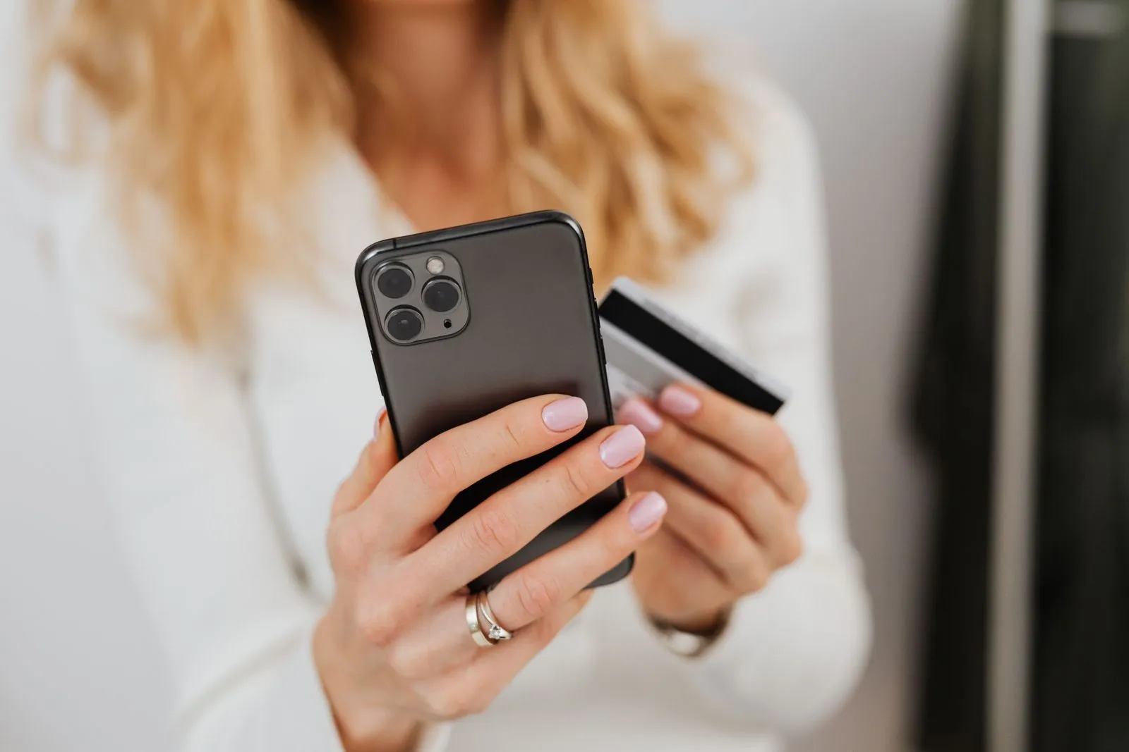 Hands holding a smartphone and a bank card to pay online