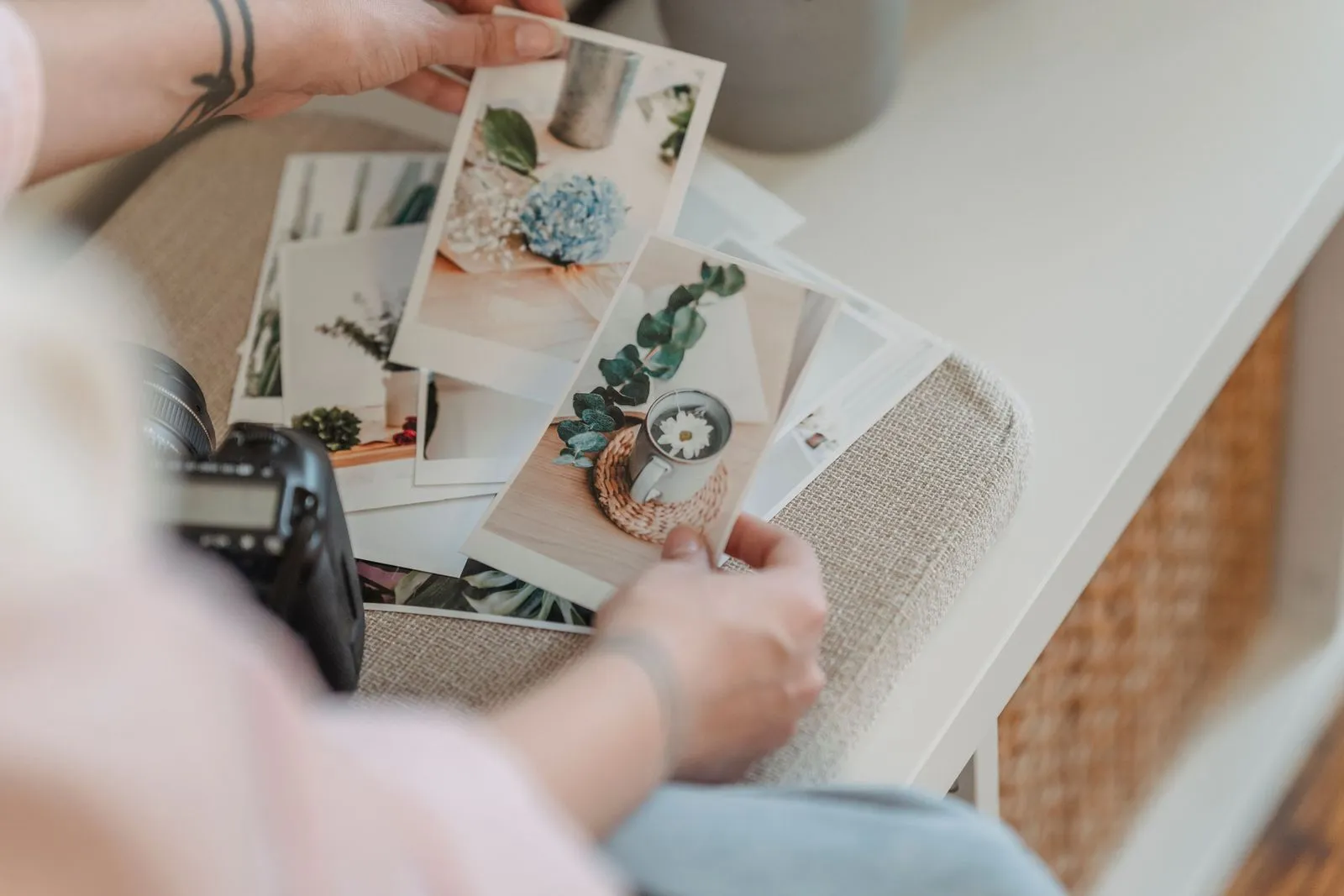 Two hands sort printed photos on a light table, with a camera beside them
