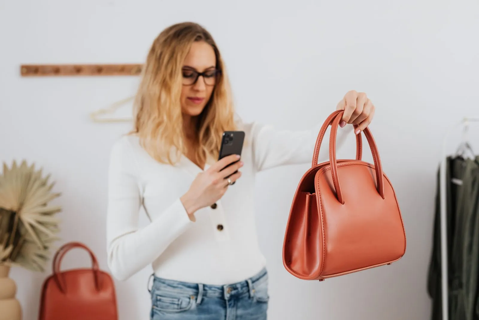 Woman taking a phone photo of a leather handbag she wants to sell online