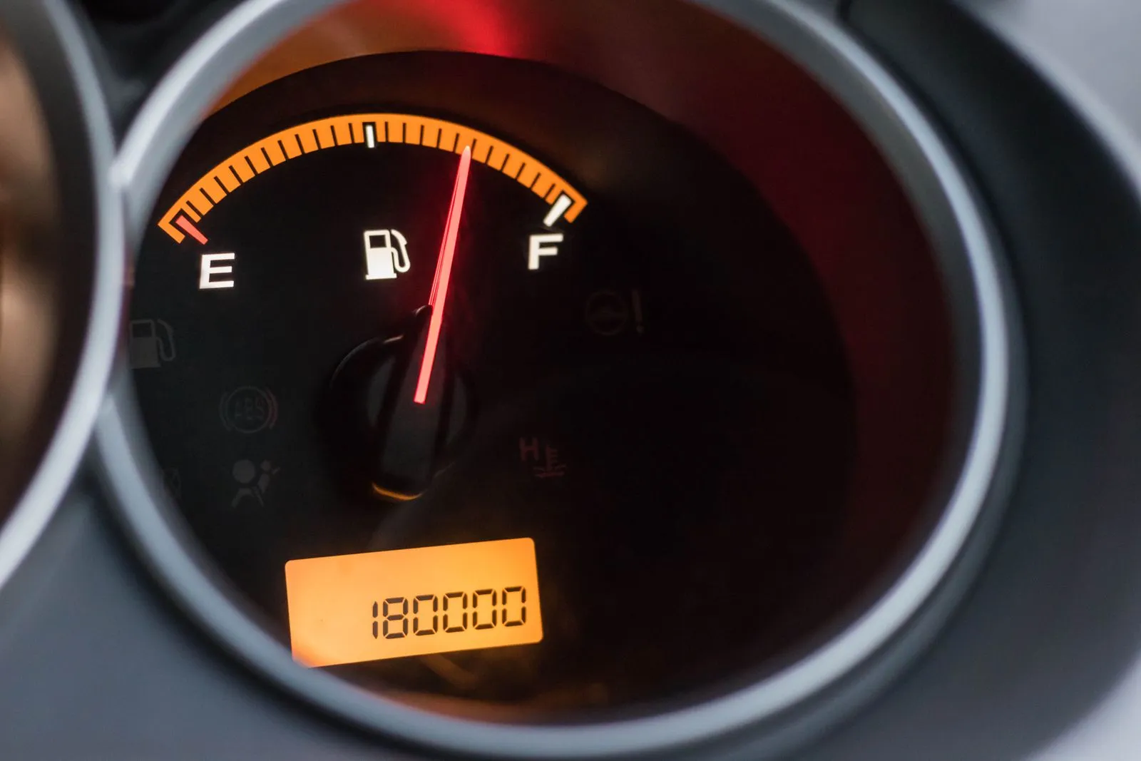 Car fuel gauge with the needle between half and full, with the odometer display below it