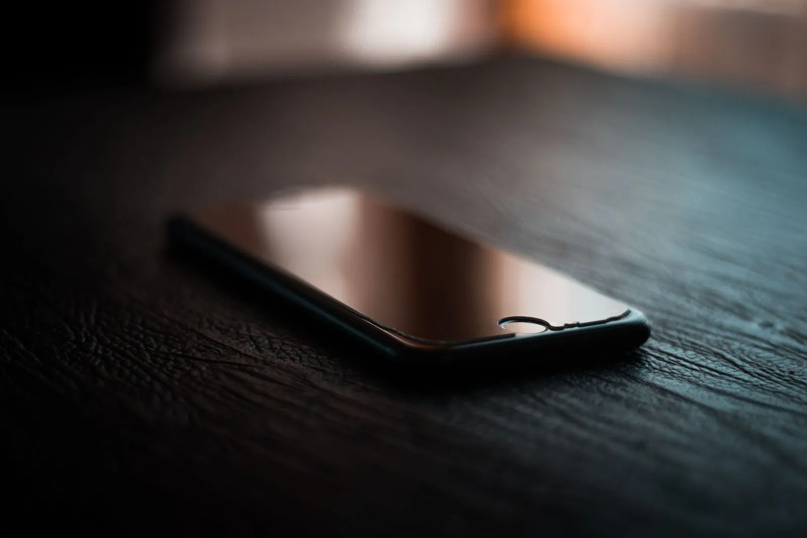 Switched-off smartphone lying on a dark table in dim light